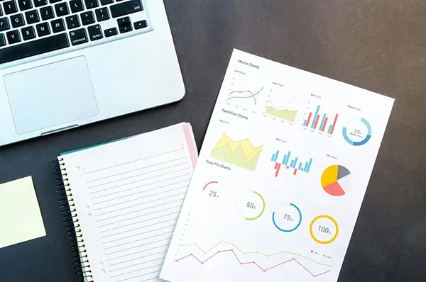 Workspace with a laptop, a spiral-bound notebook, and a data sheet displaying Morris Charts, Sparkline Charts, and Easy Pie Charts, illustrating professional chart analysis and data visualization.