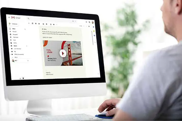 Desktop computer screen showing Gmail interface with an email addressed to John announcing a new feature. Includes an embedded video thumbnail of the Golden Gate Bridge for a video introduction.