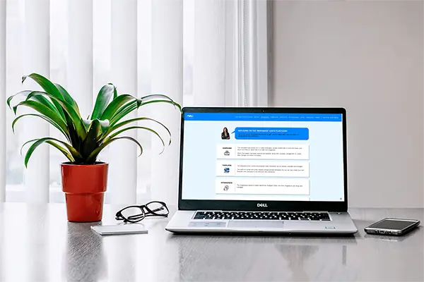 Workspace featuring a laptop open to the Mediavine Video Platform webpage, with a plant in a red pot, glasses, and a smartphone on a desk for an organized and productive setup.