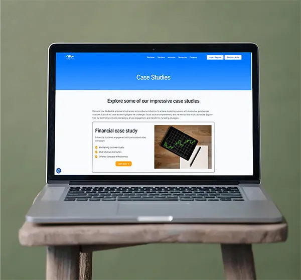 Laptop on a wooden desk showing the Mediawide case studies webpage, including a navigation bar, descriptive text on marketing success, and a financial case study with a Learn More button.