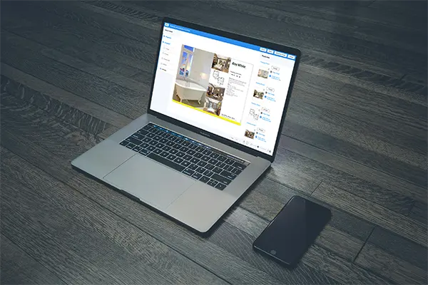 Laptop on a wooden floor displaying a real estate management tool with options for document management, property details, photos, floor plans, and agent contact, accompanied by a smartphone.